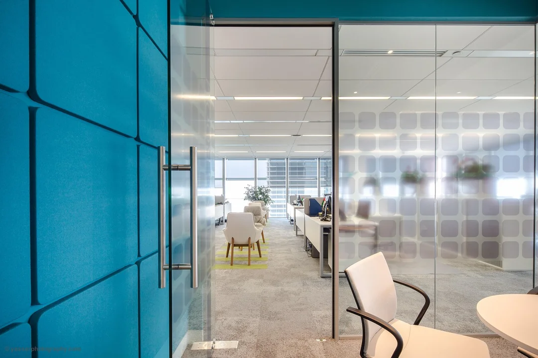 Modern office conference room with glass walls and a blue entry door.