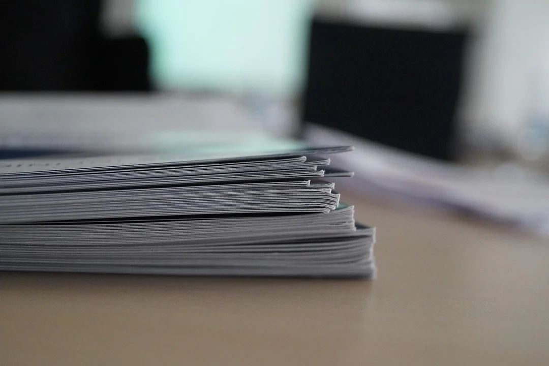 Close-up of a stack of documents on a desk with a blurred office background