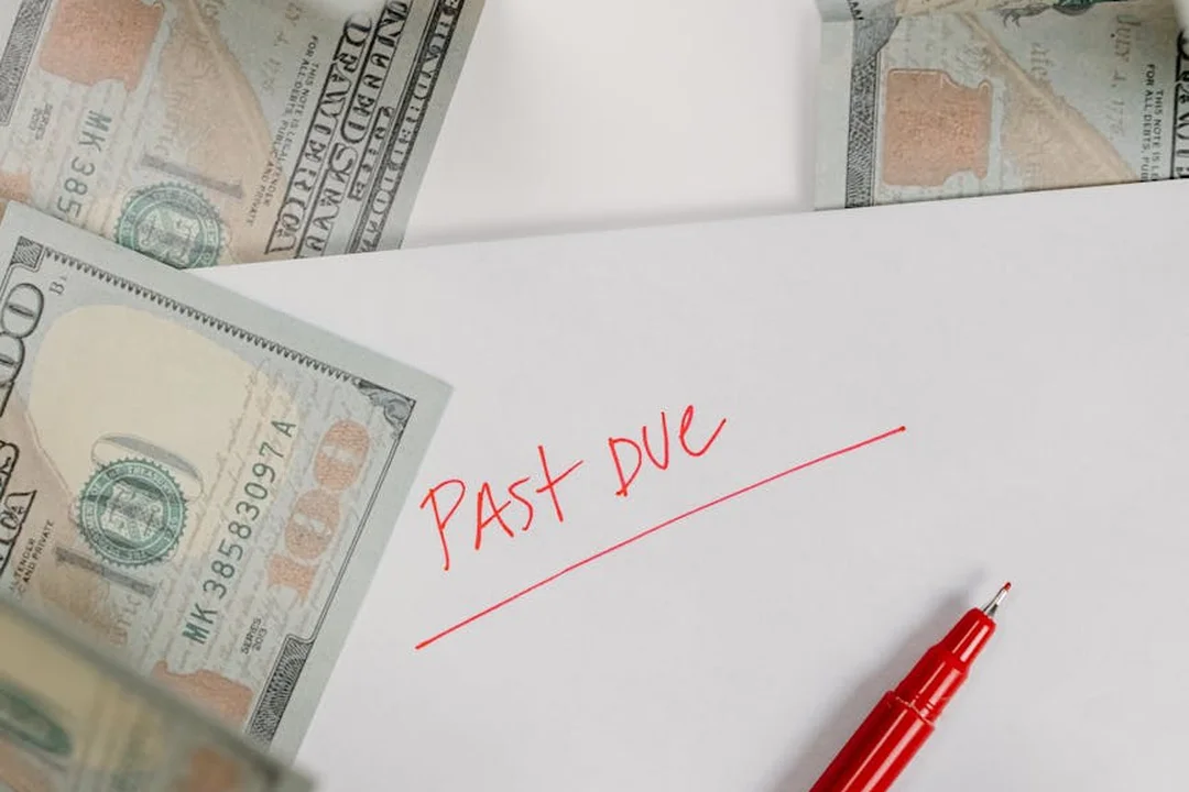 Past-due notice with a red pen, surrounded by scattered dollar bills