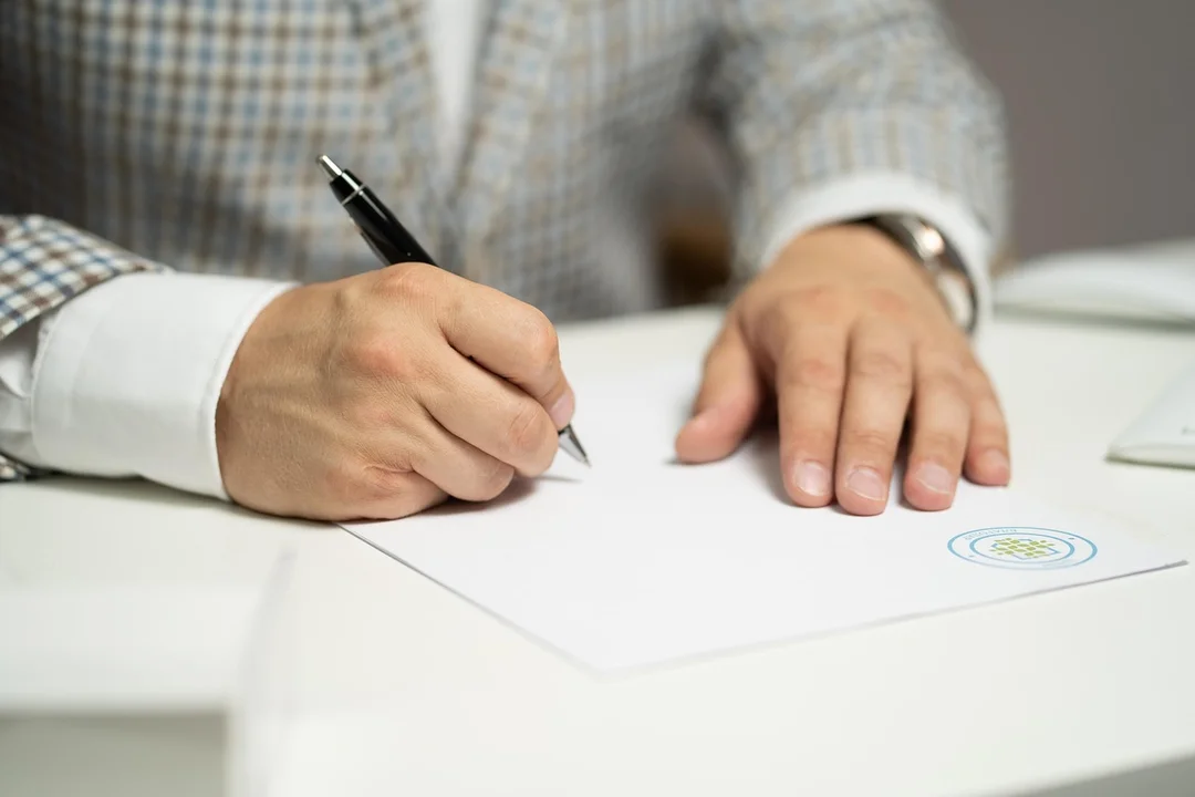 Close-up of a person signing a document at a desk, representing tenant financial obligations in an HOA.