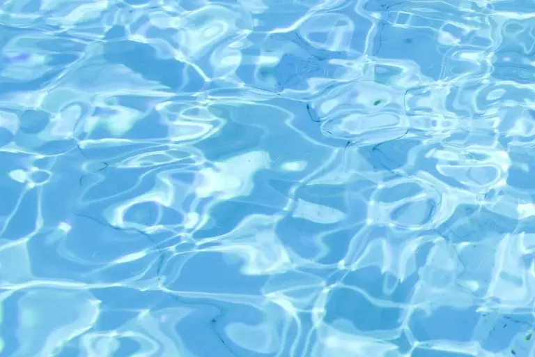 Close-up view of a blue swimming pool surface with light reflections