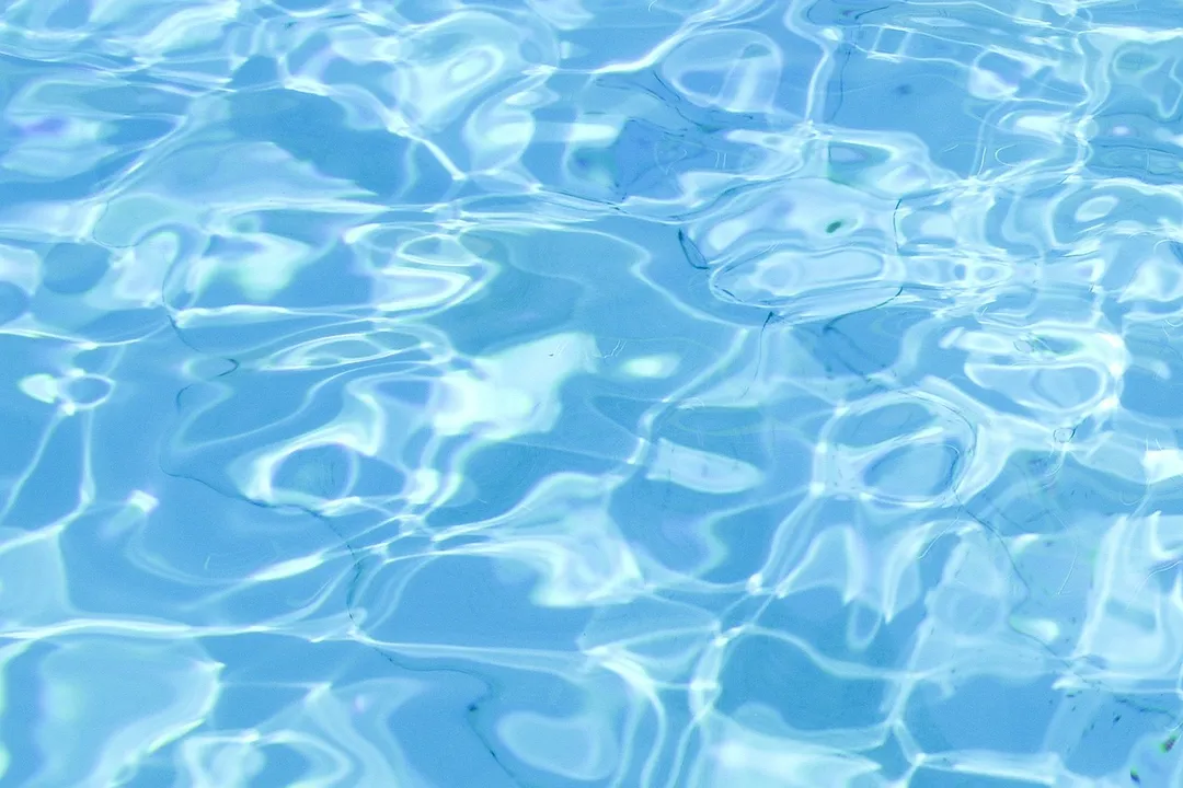Close-up view of a blue swimming pool surface with light reflections