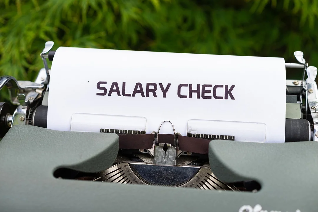 Close-up of a typewriter with a printed 'SALARY CHECK' slip, symbolizing compensation for HOA board members.