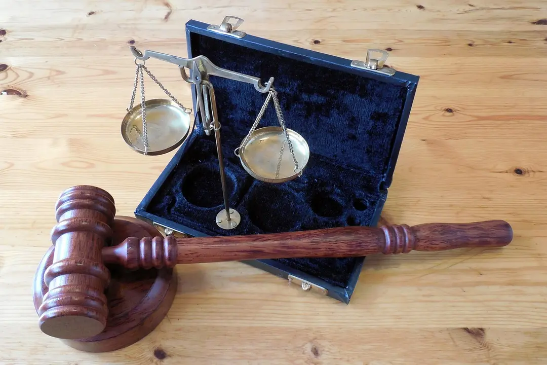 Gavel and scales of justice inside an open blue case on a wooden surface.