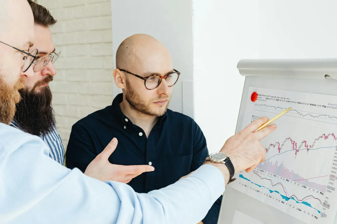 Three individuals gathered around a flip chart with graphs, discussing how to enforce HOA decisions to maintain harmony in a self-managed community.
