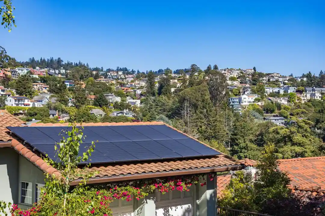 Roof with solar panels in a suburban neighborhood, with other homes and trees in the background.