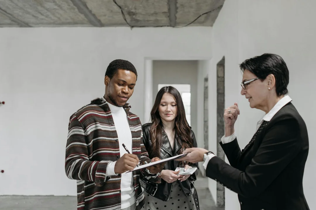Real estate agent discusses HOA documents with a couple in a hallway, illustrating how HOA rule changes can affect resaleability.