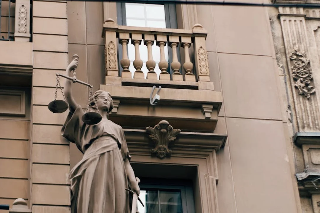 Statue of Lady Justice holding scales in front of a historic building, symbolizing law and dispute resolution.