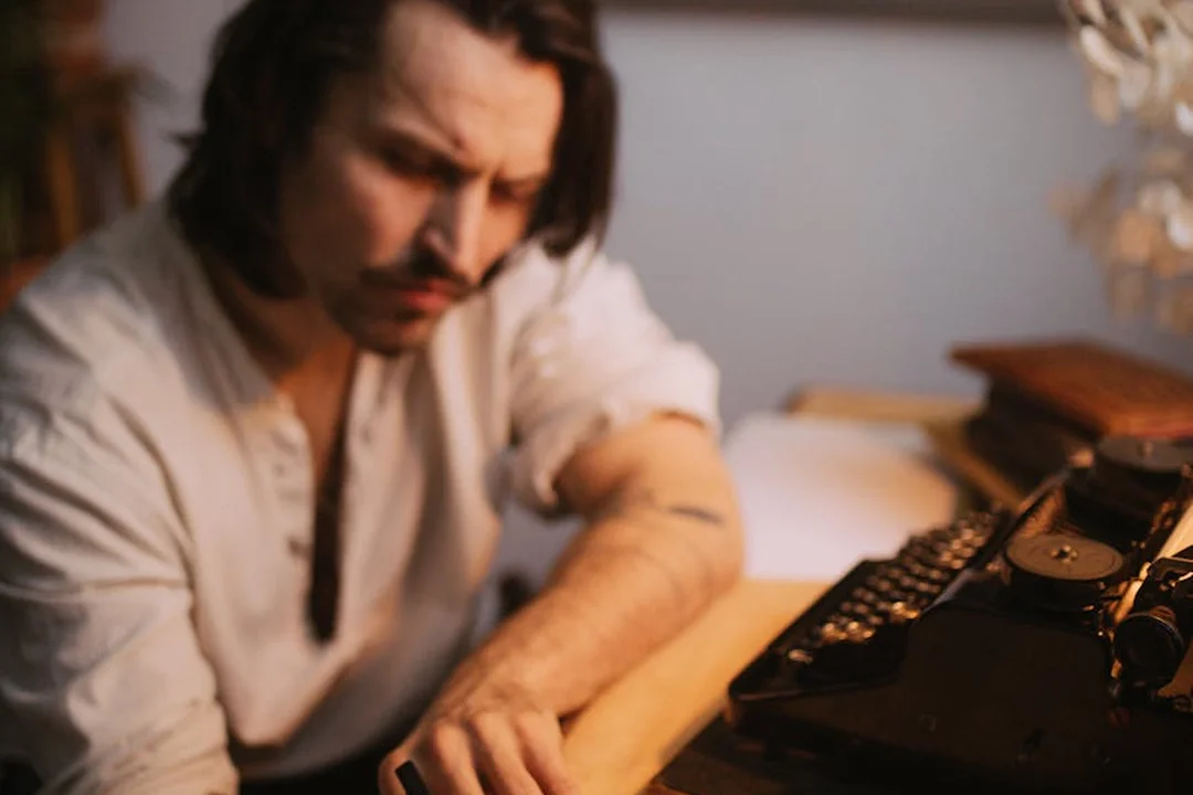 A man sits at a desk with a vintage typewriter, focused on drafting a formal letter.