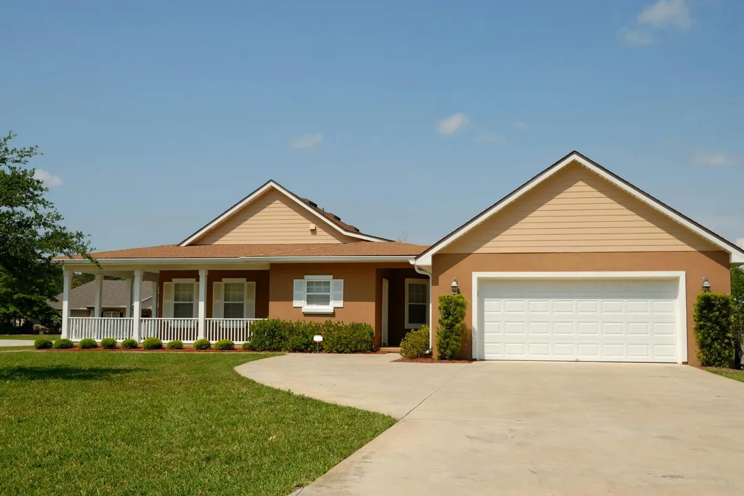 Front view of a suburban single-family home with a two-car garage, front porch, and well-manicured lawn.