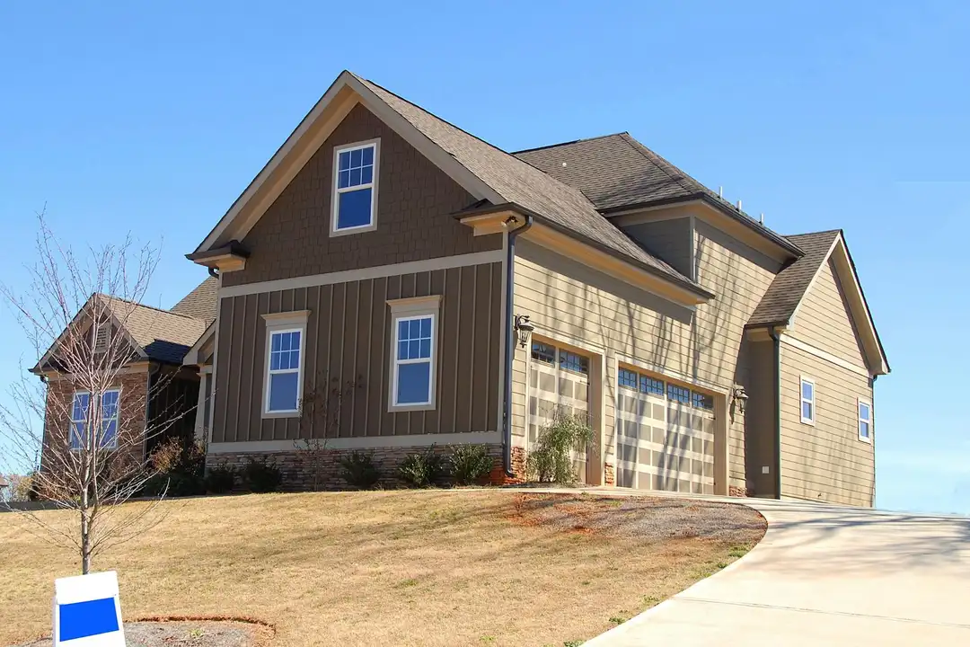 Front exterior view of a modern suburban house with a two-car garage and a sloped driveway