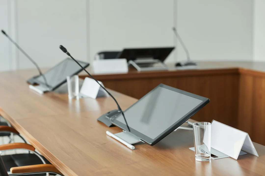 Conference room with tablets and microphones arranged on a wooden table for a HOA governance meeting.