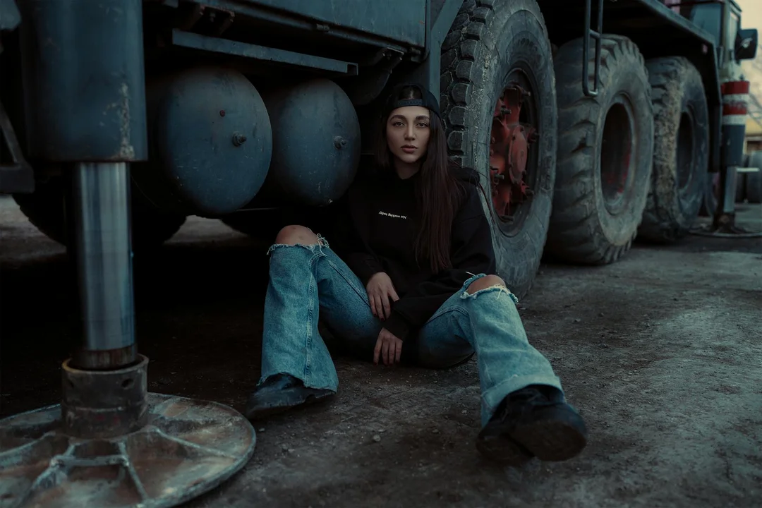 A person sits on the pavement beside a large tow truck, conveying a tense moment related to disputing a vehicle tow.