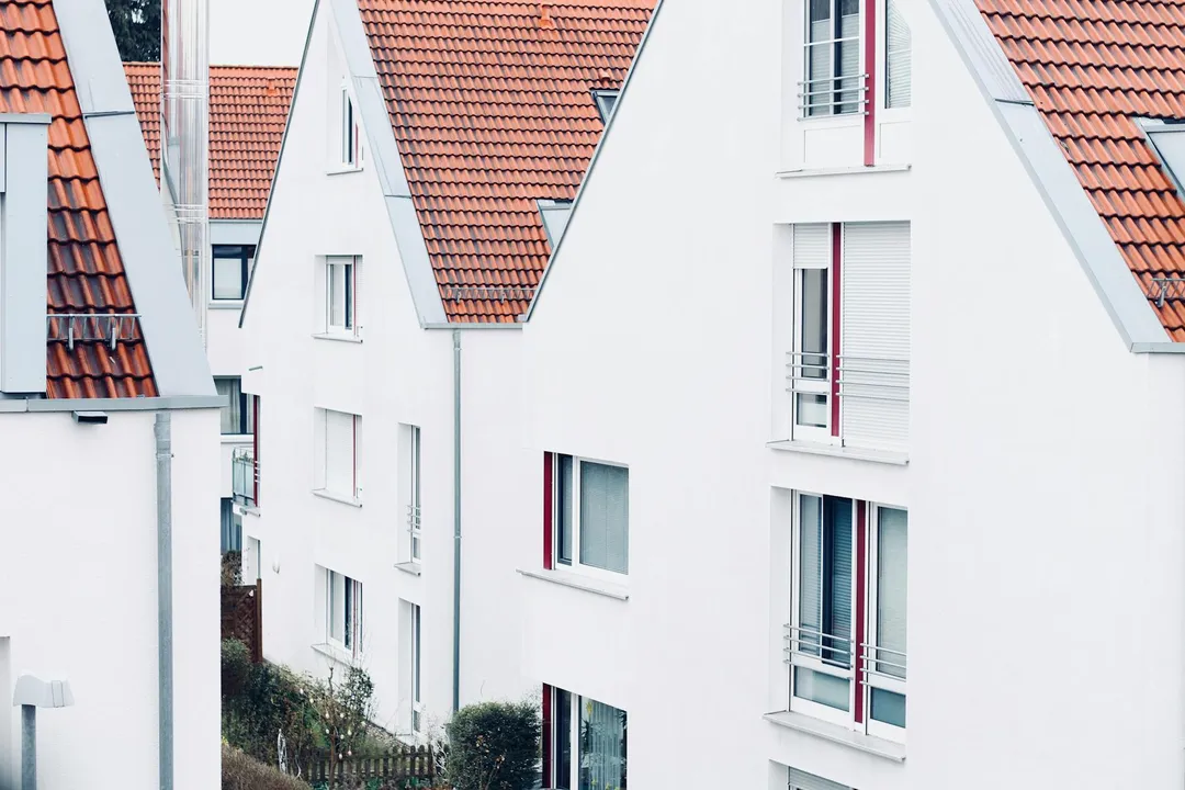 Row of white townhouses with red-tiled roofs, representing a homeowners association community.
