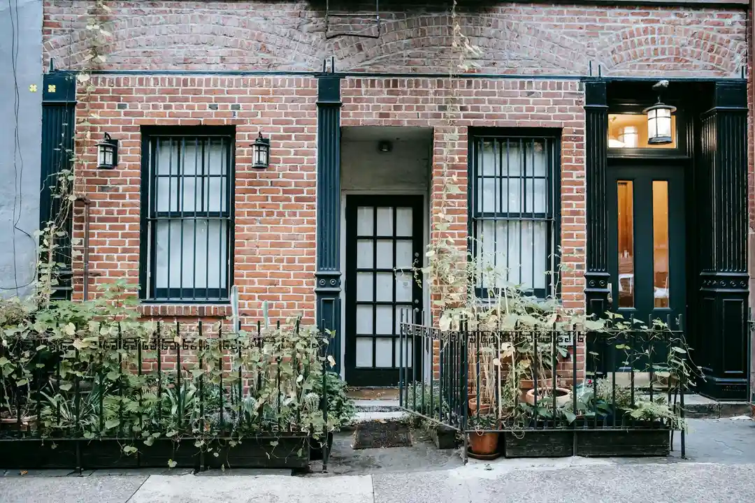 Brick townhouse façade with black-framed windows and a small front garden