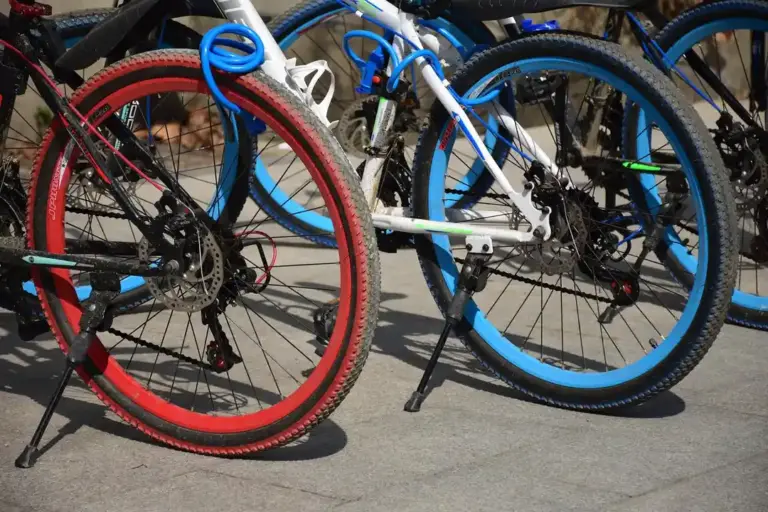 Several colorful bicycles with red and blue tires parked together in a bike rack.