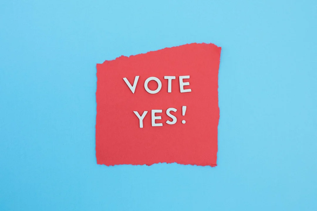 Red torn-paper note with the words 'VOTE YES!' on a blue background