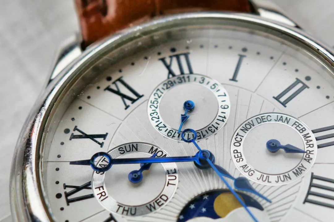 Close-up of a silver wristwatch with Roman numerals and multiple dials, symbolizing timing, deadlines, and the passage of time.