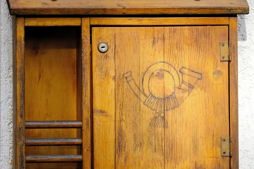 A wooden cabinet with an open left compartment and a closed right door featuring a circular carving of a figure with raised arms.